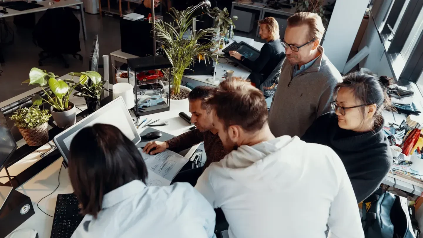 Equipo de diseño de Changan trabajando en bocetos de vehículos en un estudio, con maquetas de coches sobre la mesa